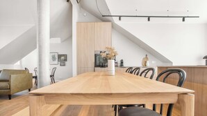 A modern dining area with a wooden table, black chairs, and a white vase with dried flowers. - Amtmann Residence - Four Bedroom Penthouse (Selfoss)