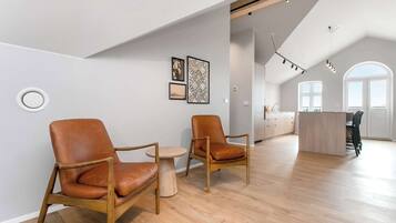 Ett rymligt rum med två läderfåtöljer, ett litet runt bord och en köksdel i bakgrunden.