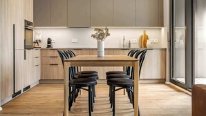 A modern kitchen with wooden cabinets, a central island with chairs, and a vase of dried flowers.