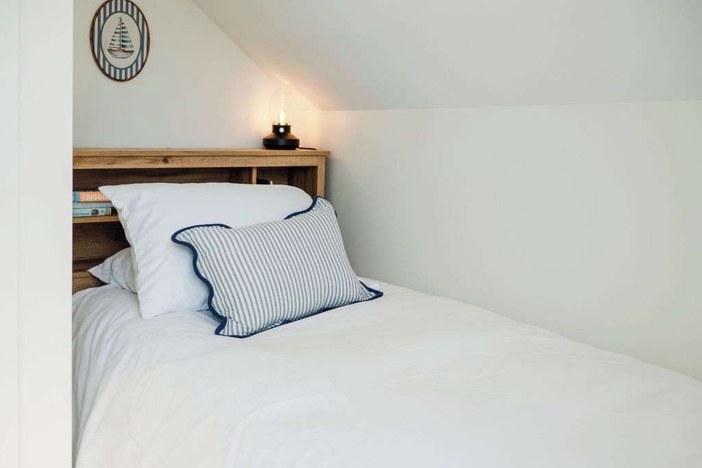 Quarto com cama, mesa de cabeceira e luminária na parede.