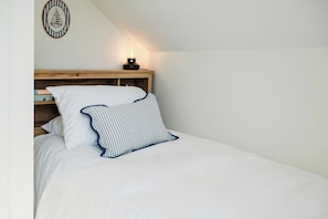 A bedroom with a bed, a nightstand, and a wall-mounted lamp.