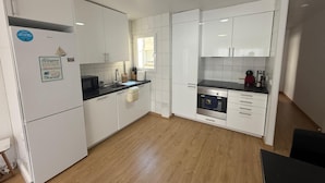 A modern kitchen with white cabinets, a black countertop, and a built-in oven. - Ramon Apartment (Tarragona)