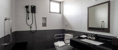 A modern bathroom with a black and white color scheme, a large mirror, a toilet, a bidet, and a shower area.
