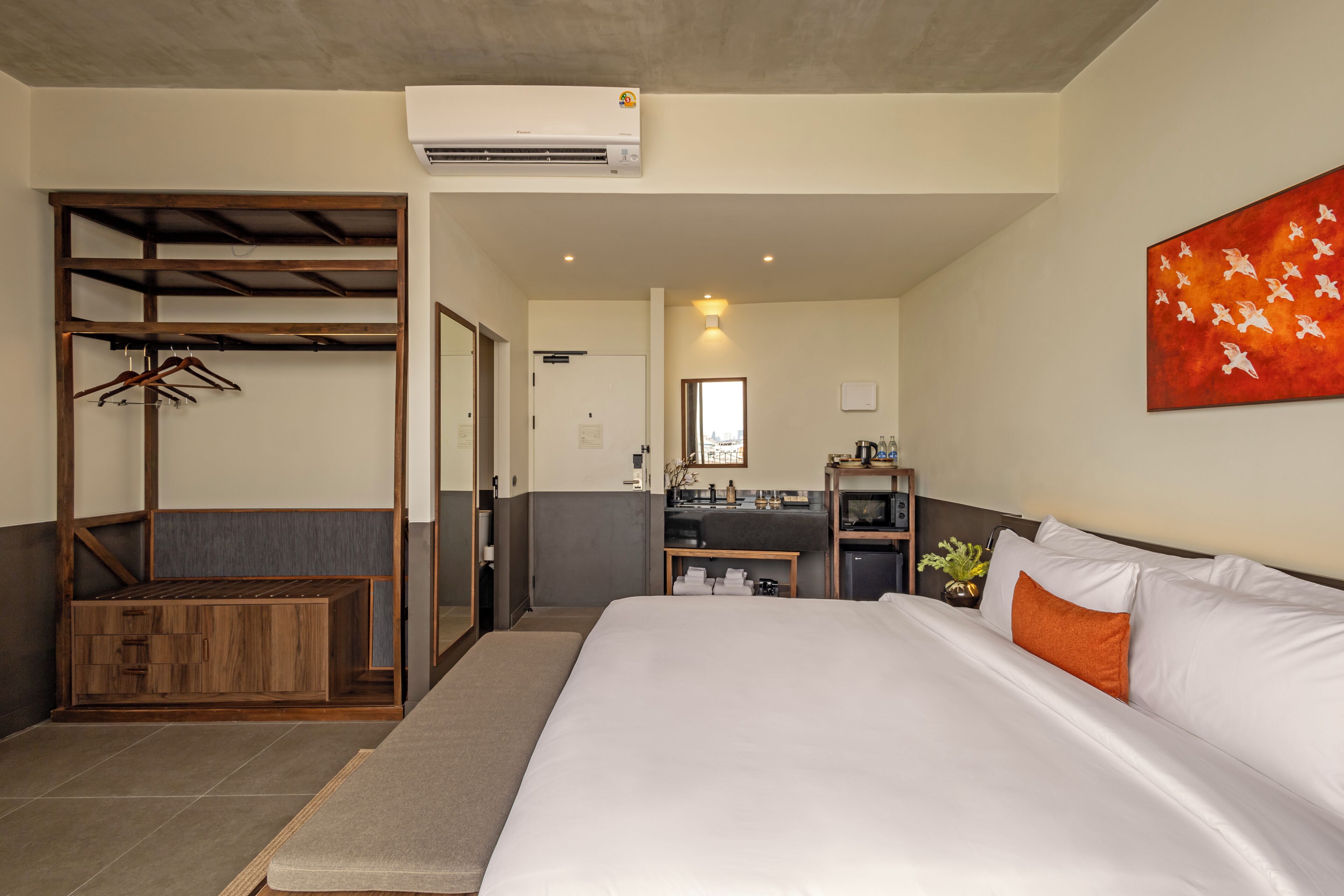 Habitación de hotel con cama, armario de madera, kitchenette y baño.