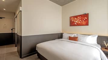 Una habitación de hotel moderna con una cama grande, una mesita de noche pequeña y un cuadro en la pared.