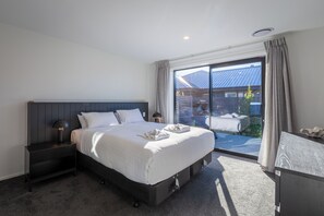 Una camera da letto con un letto grande, un comodino, una lampada, vista sull'esterno e una finestra con tende.