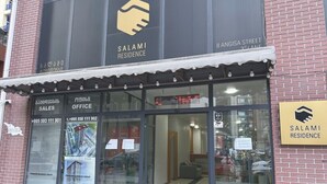 En kommersiell byggnad med en skylt som visar namnet Salami Residence, ett försäljningskontor och en reception.