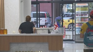 En receptionsdisk med en skylt som det står ”RECEPTION” på, en automattankstation och en bil som står parkerad utanför.