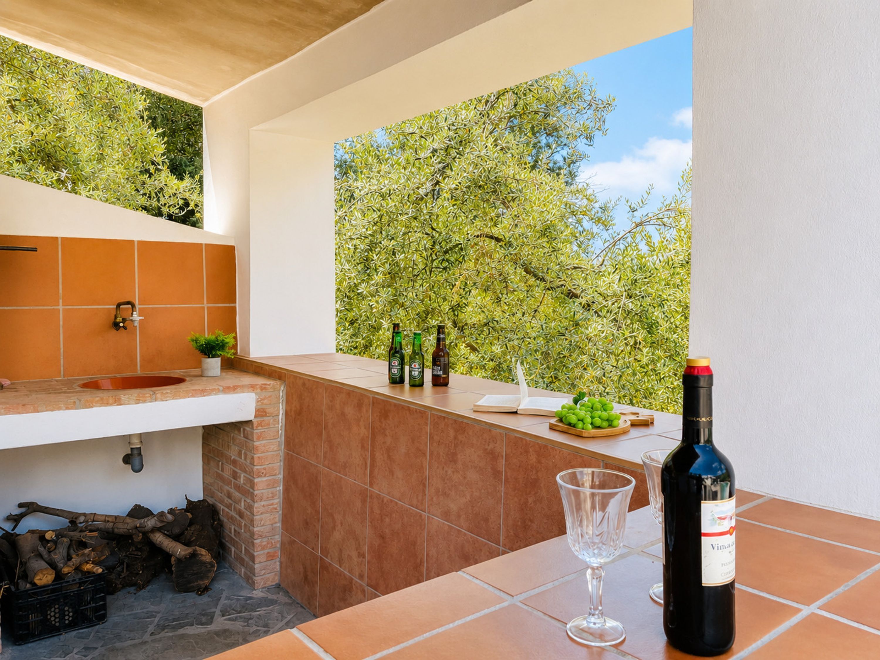 Una cocina exterior moderna con un lavamanos, una botella de vino y una copa.