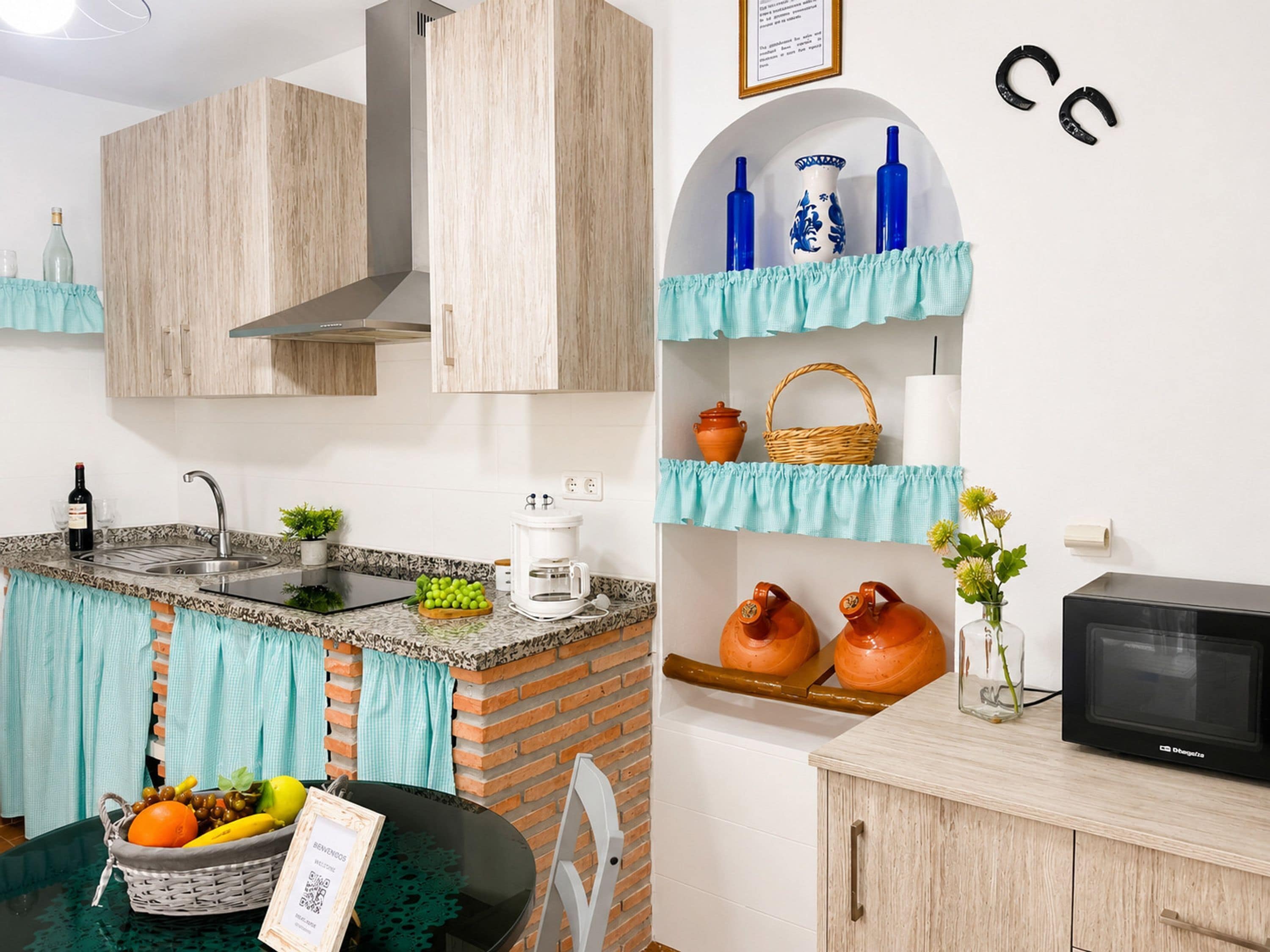 A modern kitchen with a sink, stove, and microwave. There are decorative items on shelves and a basket on the counter.
