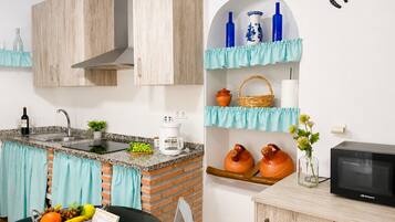 A modern kitchen with a sink, stove, and microwave. There are decorative items on shelves and a basket on the counter.
