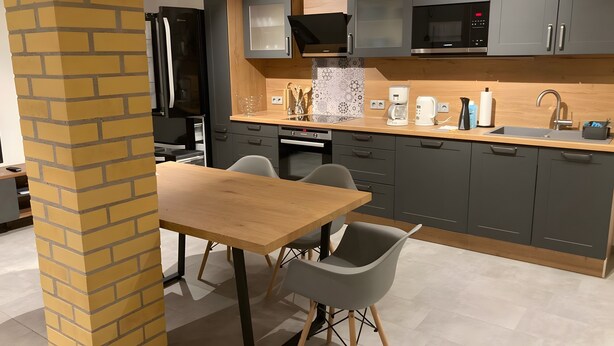 A modern kitchen with grey cabinets, a black refrigerator, a microwave, and a coffee maker.
