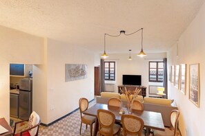 Zona pranzo con tavolo, sedie e televisione sullo sfondo.