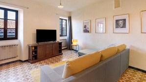 A living room with a sofa, a television, a cabinet, and framed pictures on the wall.