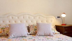 A bed with a floral-patterned bedspread, a tufted headboard, and two white pillows.