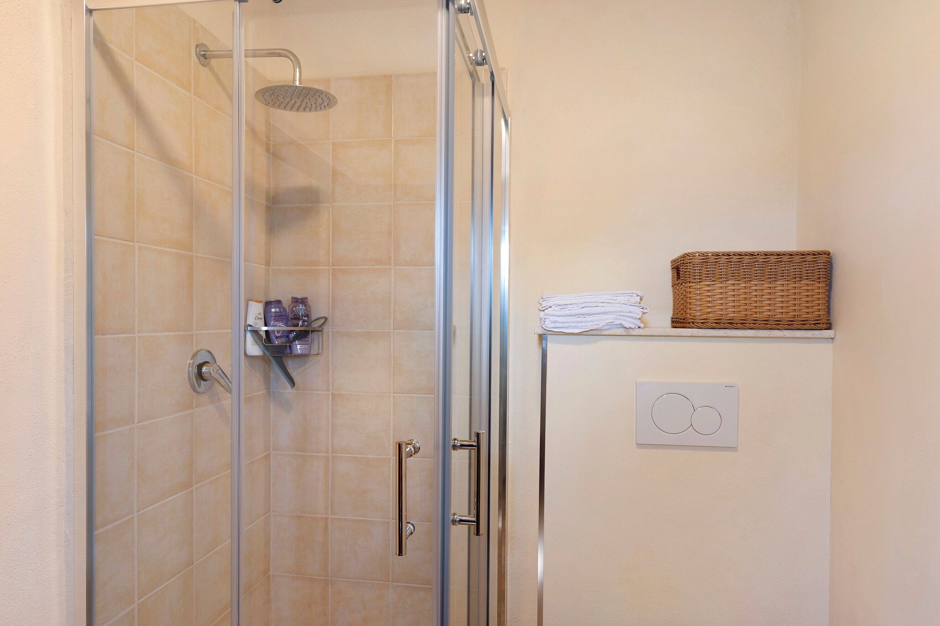 A shower with a glass door, a white cabinet with a basket, and a towel rack.