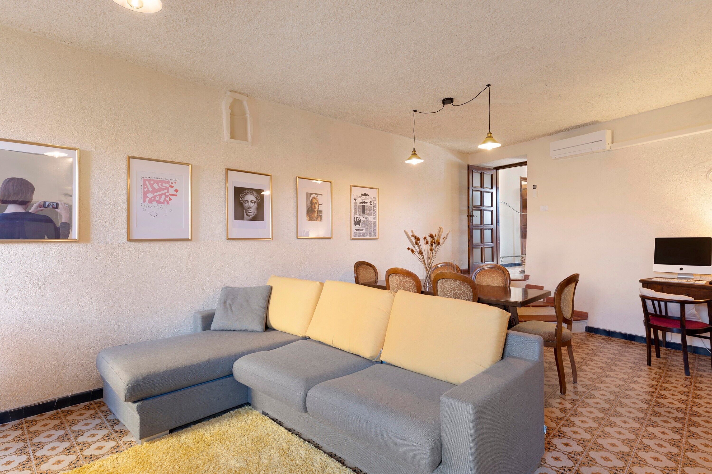 Una sala de estar con sofá, mesa de comedor, sillas y televisor.
