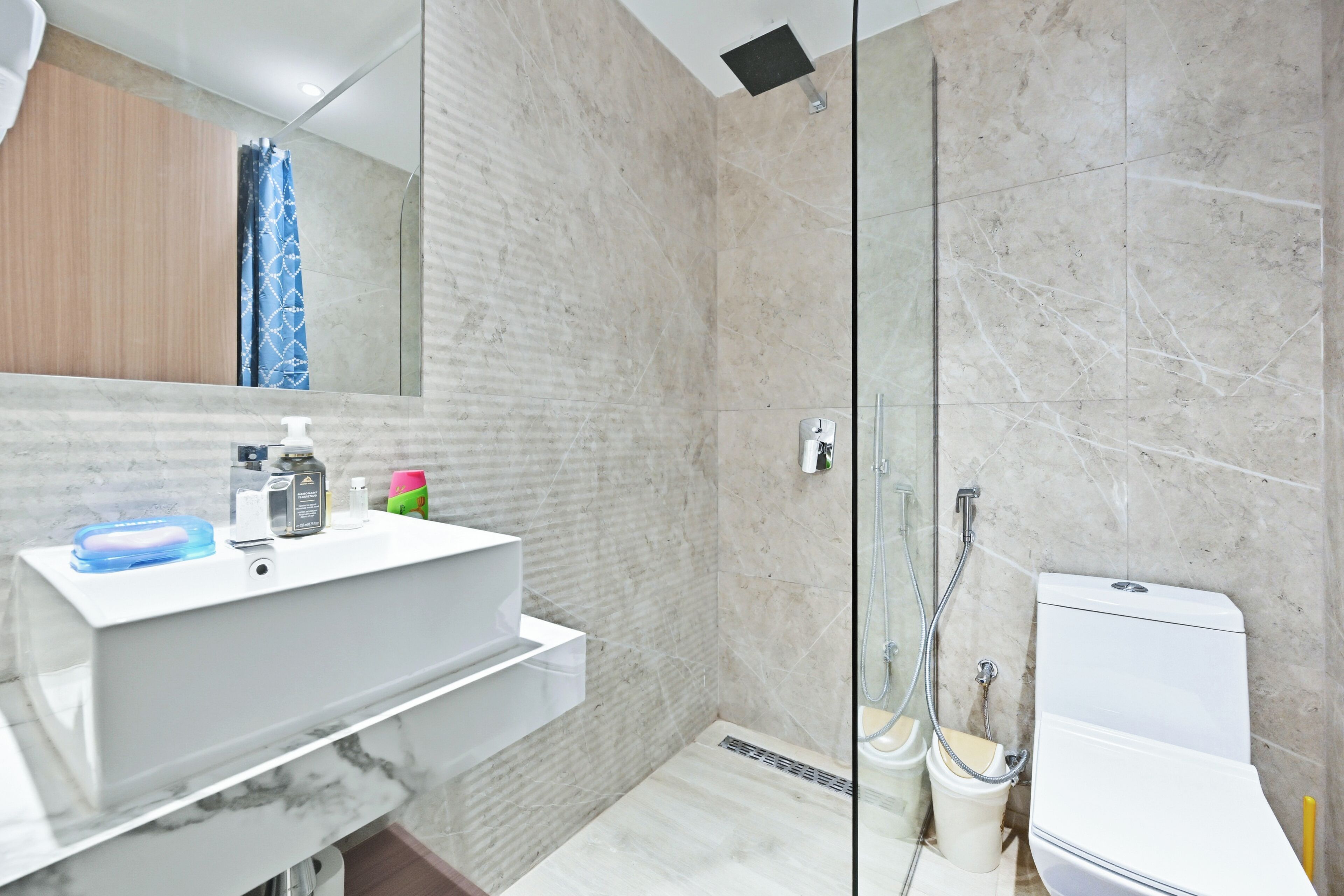 A bathroom with a marble sink, a shower, and a toilet.