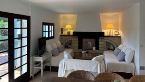 A cozy room with a fireplace, two sofas, a small table, and a chair. - Charming Villa in Cap-Ferret (Lège-Cap-Ferret)