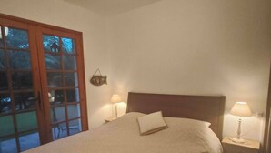 A bedroom with a bed, two bedside lamps, a hanging light fixture, and a wooden door. - Charming Villa in Cap-Ferret (Lège-Cap-Ferret)