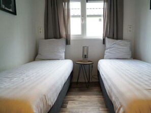 A small, clean room with two single beds, a small table, and a window with curtains. - Holiday Home in Kampen With Terrace (Kampen)