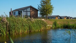 A modern building with large windows, a grassy area, and a body of water. - Holiday Home in Kampen With Terrace (Kampen)