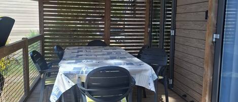 A covered patio with a table and chairs, a wooden deck, and a sliding glass door.