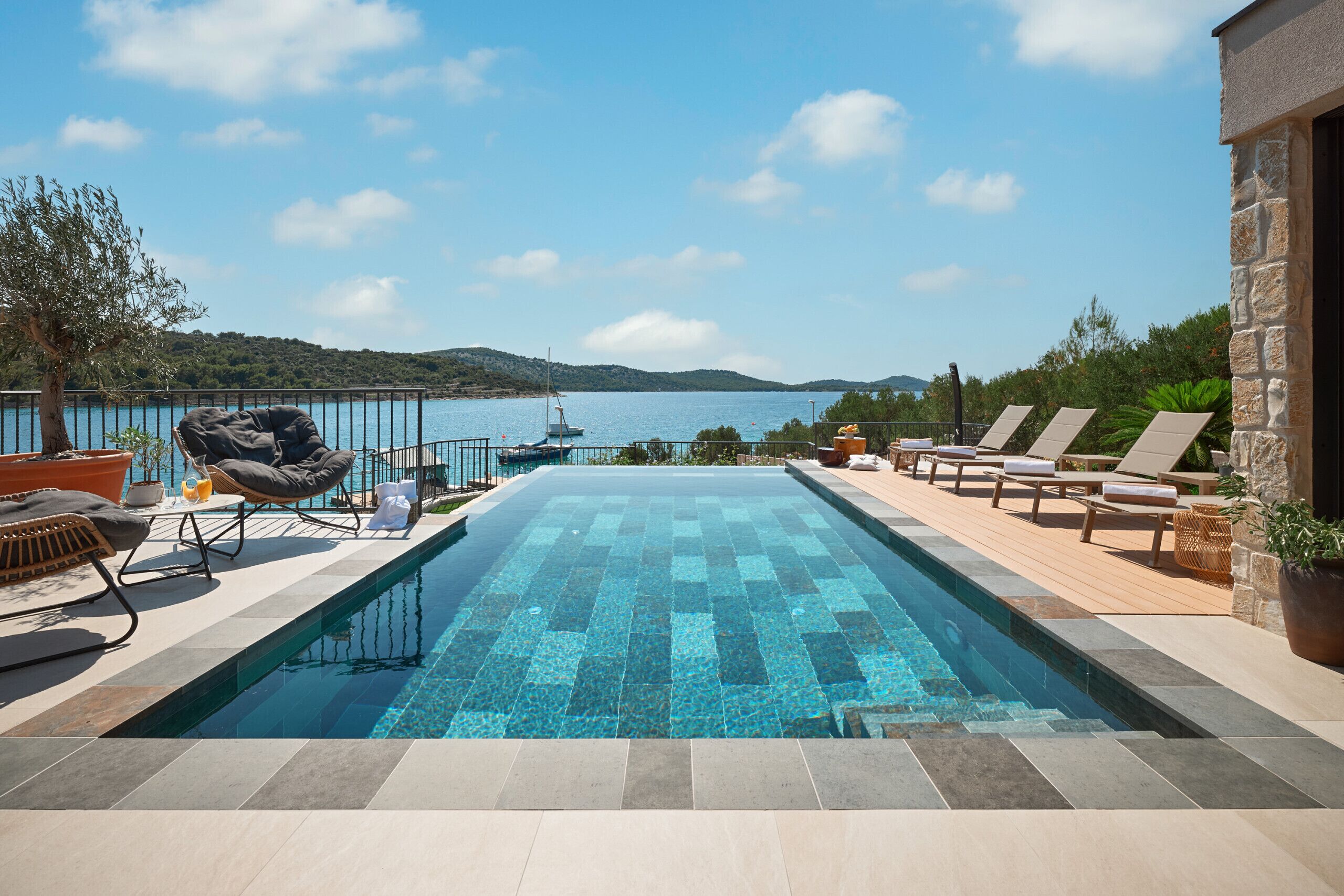 A swimming pool with lounge chairs and a view of the sea.