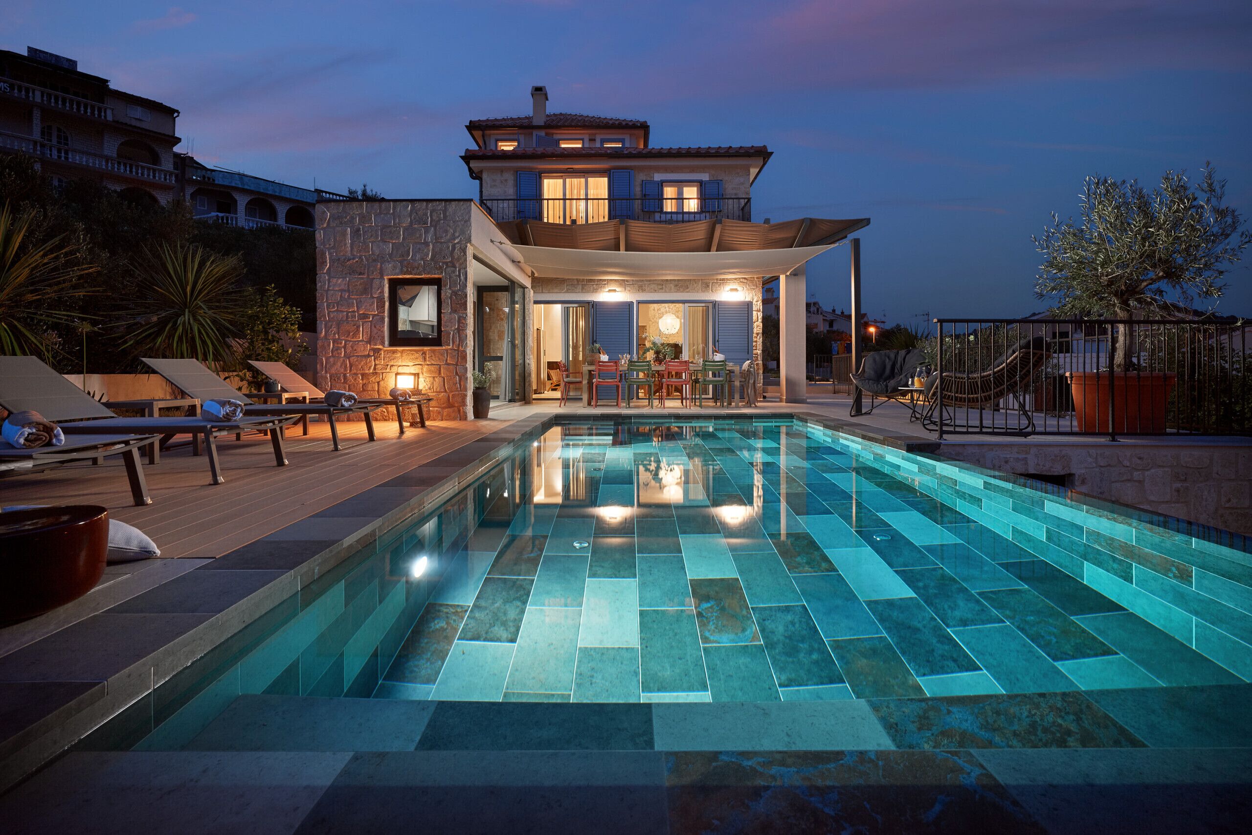 A poolside area with a stone building, lounge chairs, and a dining setup.
