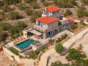 A multi-story house with a swimming pool, outdoor seating, and a stone retaining wall. - Luxury Seafront Villa Kaprije Šibenik with pool (Kaprije)