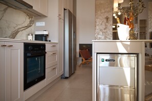 Eine moderne Küche mit Einbauofen, Kühlschrank und Kaffeemaschine auf der Arbeitsfläche.