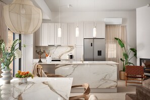 Een moderne keuken met marmeren werkbladen, roestvrijstalen apparatuur, hanglampen en een centraal eiland.