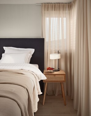 Ein Hotelzimmer mit einem Bett, einem Nachttisch mit Lampe und durchsichtigen Vorhängen.
