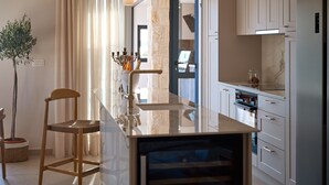 Una cucina moderna con un piano di lavoro in marmo, elettrodomestici in acciaio inossidabile e un'area pranzo con una sedia e un tavolo in legno.