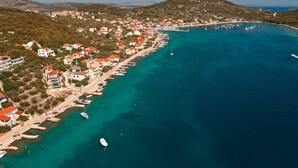 Una località costiera con edifici lungo il lungomare, barche ormeggiate e una vista limpida sul mare.