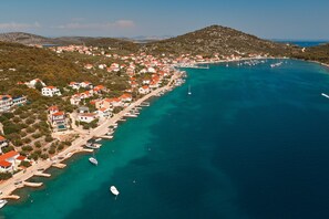 A coastal town with buildings along the waterfront, boats docked, and a clear view of the sea. - Luxury Seafront Villa Kaprije Šibenik with pool (Kaprije)