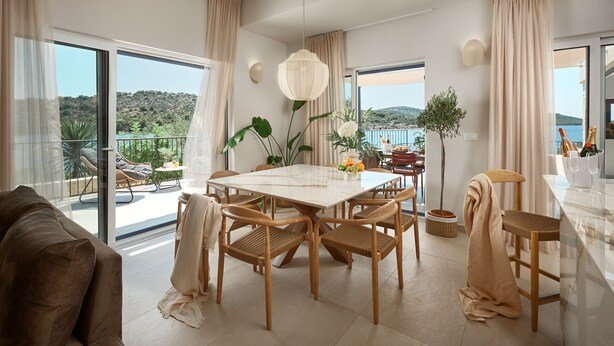 Un'ampia sala da pranzo con un tavolo grande, sedie di legno e vista sul mare.