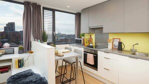 Una cocina moderna con vista a la ciudad, un comedor con taburetes y una zona de estar acogedora con una alfombra mullida.
