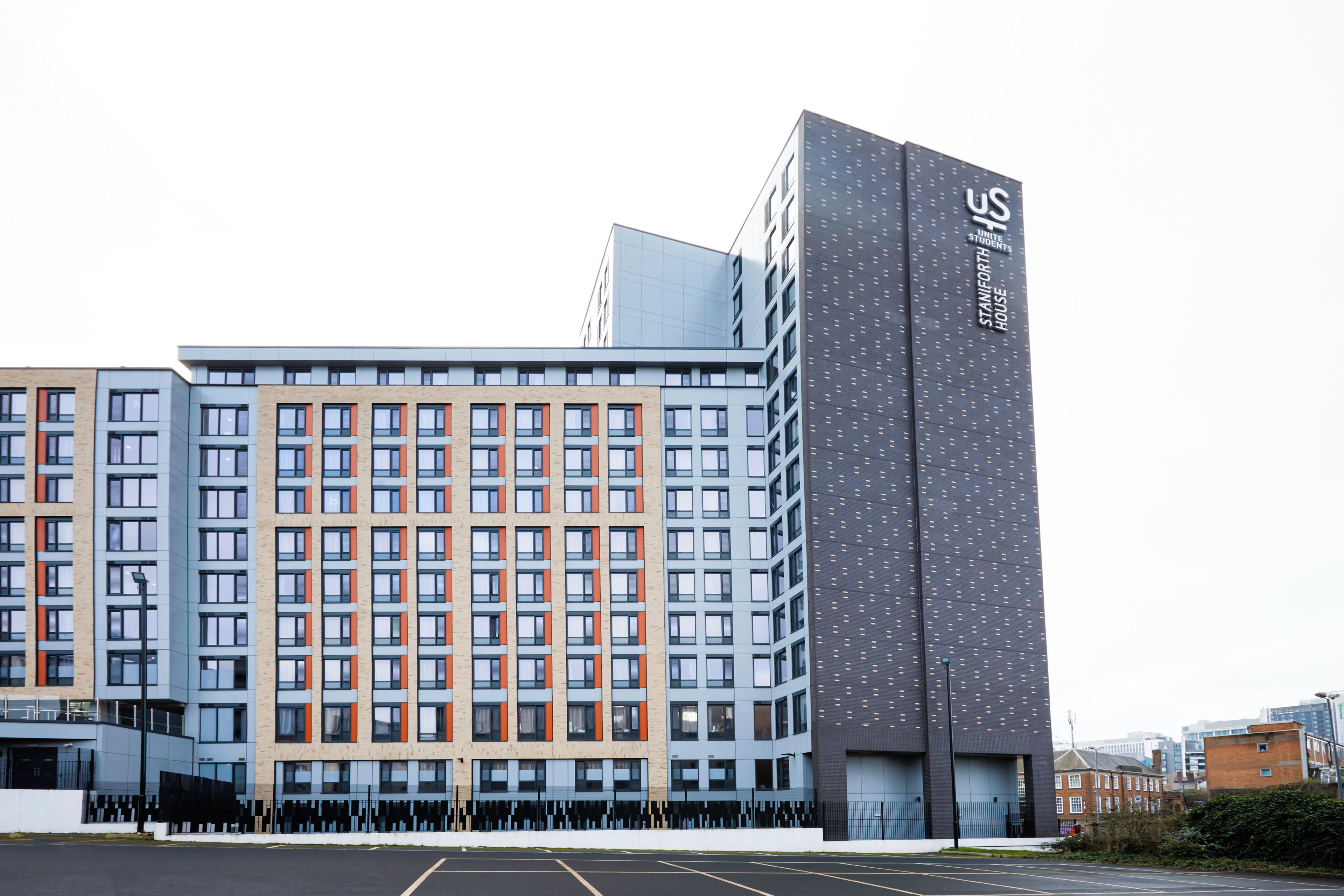 A modern multi-story hotel with a mix of residential and commercial units, featuring a prominent entrance and a tall building with a unique facade.