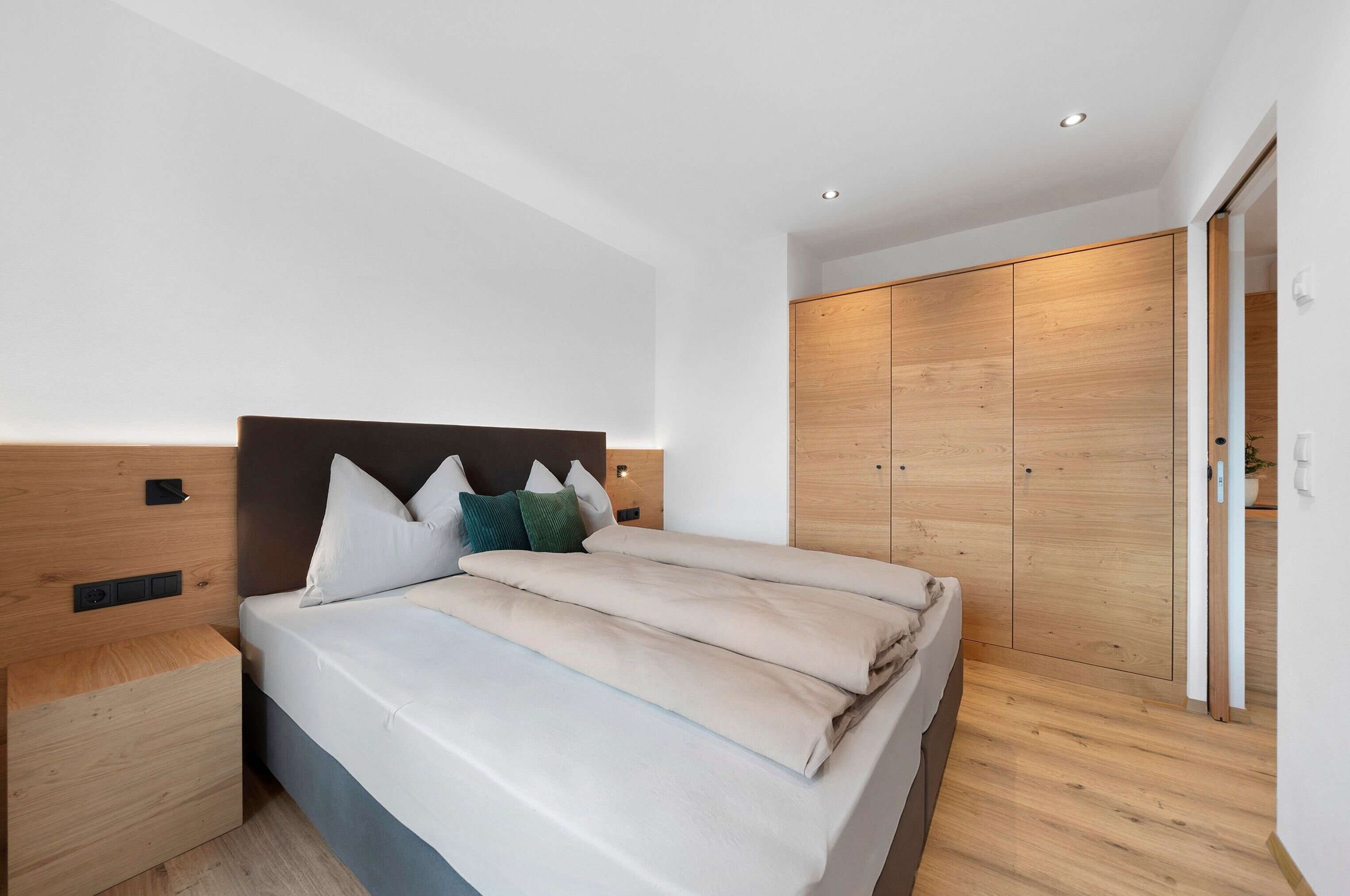 Un dormitorio moderno con cama, mesitas de noche y armario.