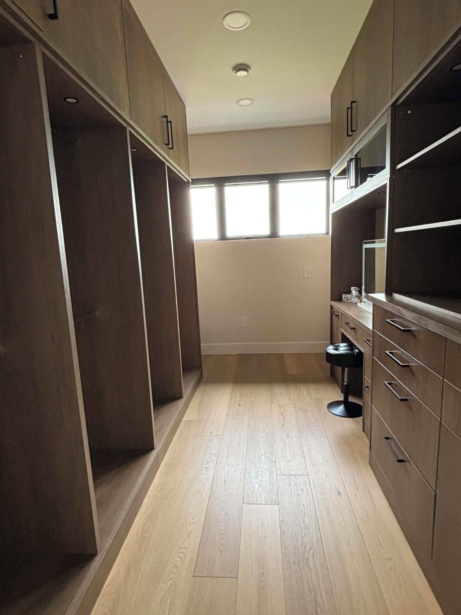 Un armario vestidor con armarios de madera y un espejo.