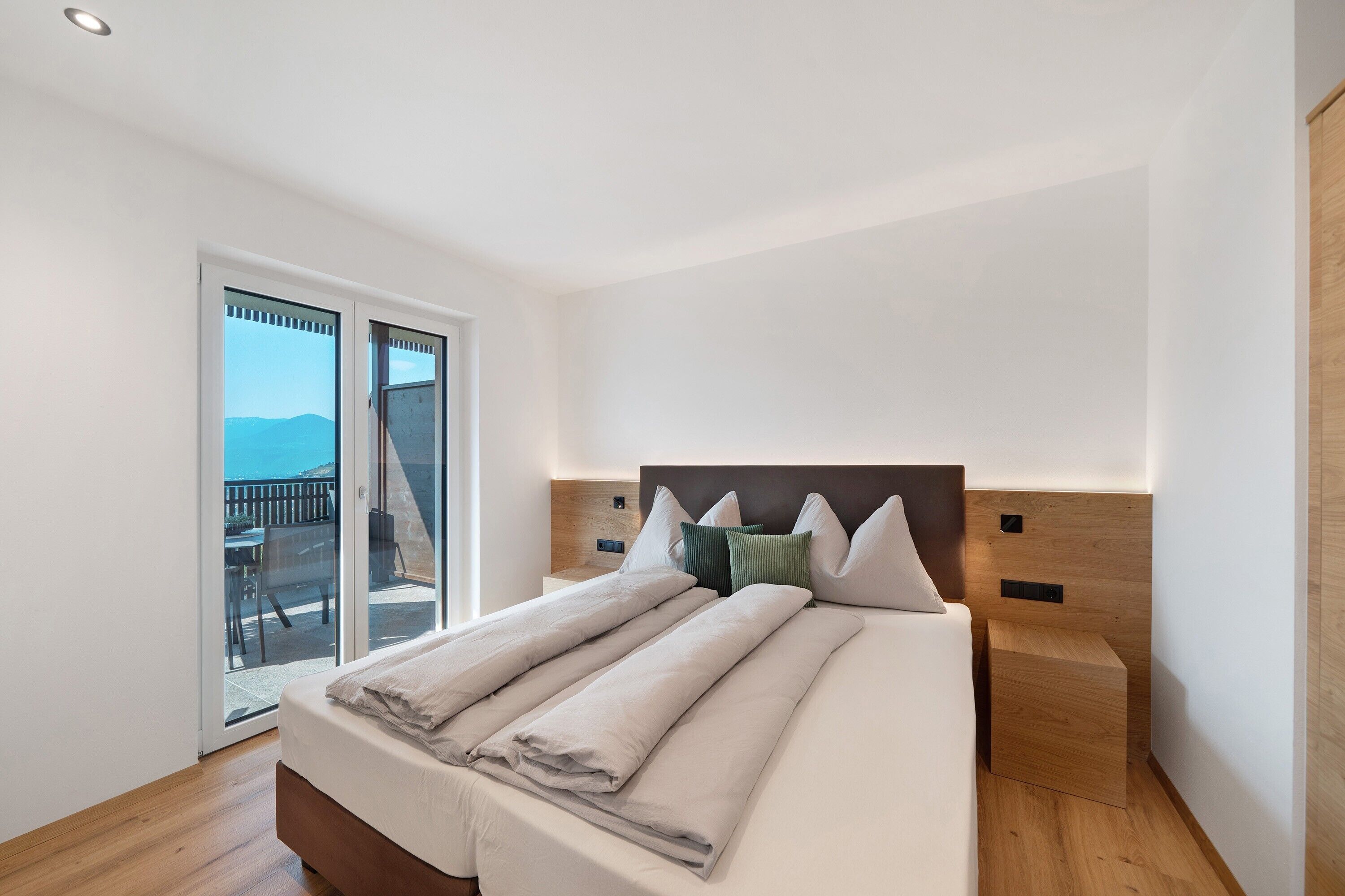 A bedroom with a bed, a nightstand, and a view of the outdoors.