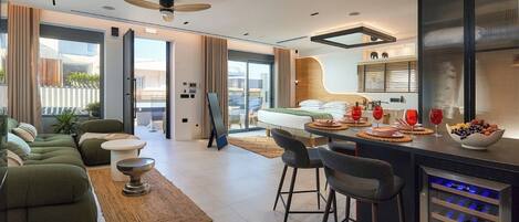 Ein modernes Hotelzimmer mit einer Sitzecke, Essbereich und einer Minibar.