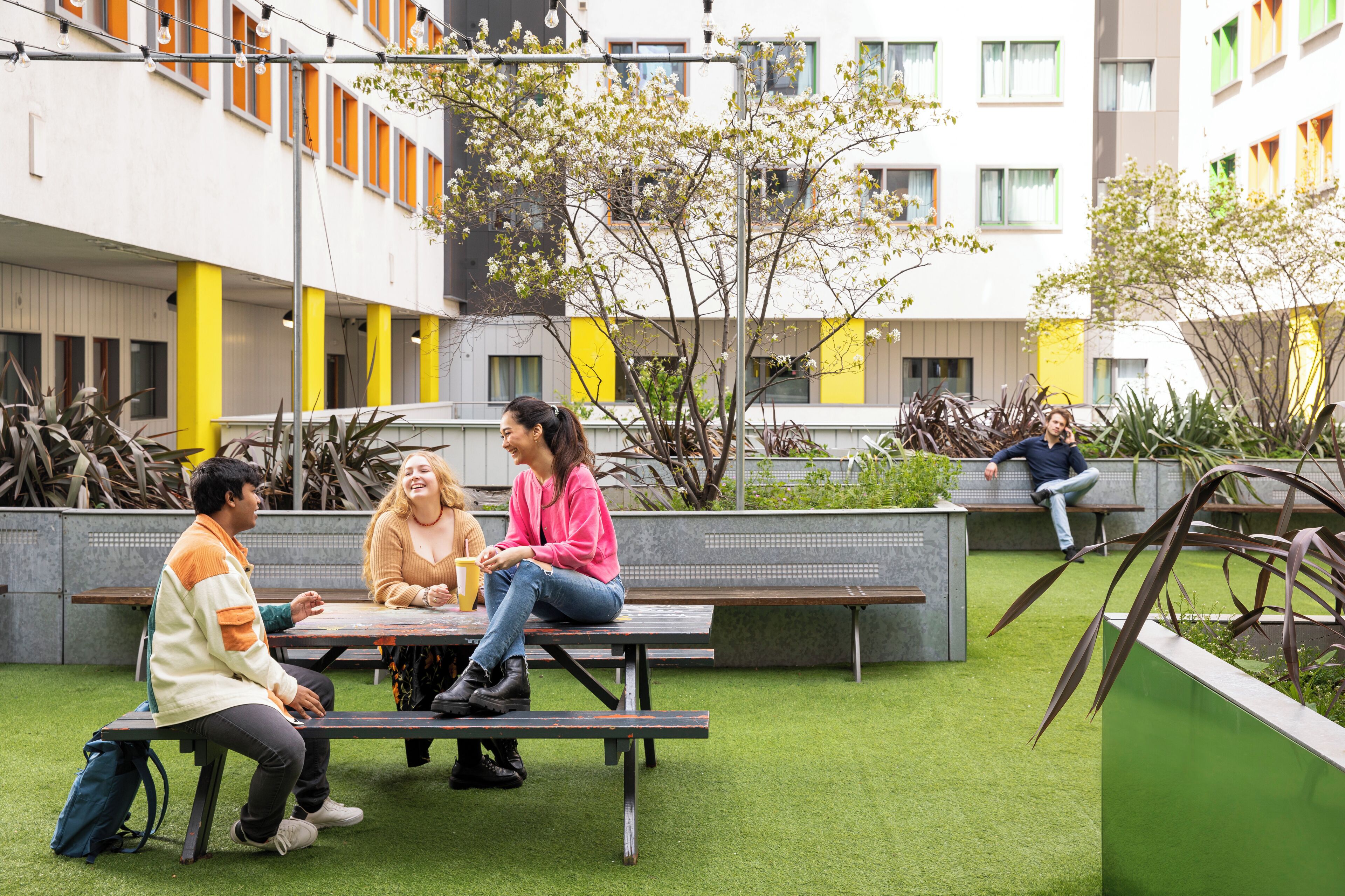 A courtyard with a picnic table, benches, and a building with multiple windows and balconies.