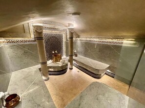A bathroom with marble flooring, a decorative tile pattern, and a central column.