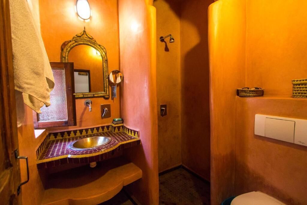 A bathroom with a sink, mirror, towel, and toilet.