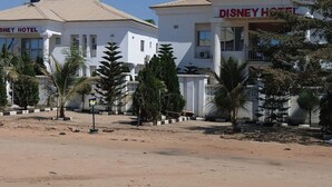 Deux bâtiments portant les inscriptions « SNEEY HOTEL » et « DISNEY HOTEL », avec un ciel dégagé et des palmiers au premier plan.