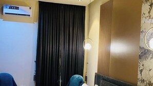 Une chambre d’hôtel équipée d’un lit, d’un bureau, d’une chaise, d’un appareil de climatisation et d’un luminaire fixé au mur.