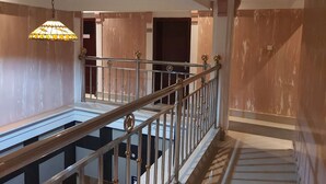 Un escalier avec une rampe en métal, un luminaire suspendu et une vue sur une pièce dotée d’un plancher et de murs en bois.