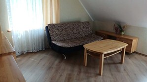 A room with a sofa, a wooden table, a wooden cabinet, and a window with curtains. - 2-bedroom apartment in lovely Ventspils with air conditioning 1 (Ventspils)